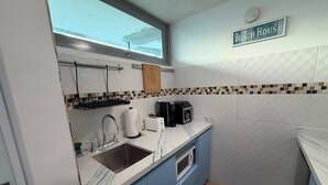 Una cucina compatta con lavandino, macchina del caffè e microonde.