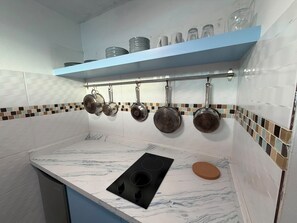 A kitchen with a white marble countertop, a black induction cooktop, and pots hanging on a rack. - One minute walk to the beach! (Luquillo)