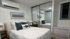 Una camera da letto con un letto, comodini, uno specchio e un condizionatore d'aria.