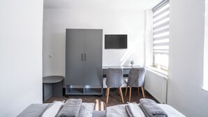 A modern hotel room with a bed, a desk, a chair, and a wardrobe. - Duisburger Hostel (Duisburg)