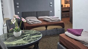 A modern bedroom with a bed, a sofa, a dining table with a vase of flowers, and a small kitchen area. - Duisburger Hostel (Duisburg)