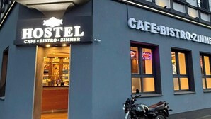 A building with a sign reading "HOSTEL CAFE BISTRO ZIMMER" and a motorcycle parked in front. - Duisburger Hostel (Duisburg)