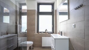 A modern bathroom with a toilet, sink, and window. - Duisburger Hostel (Duisburg)