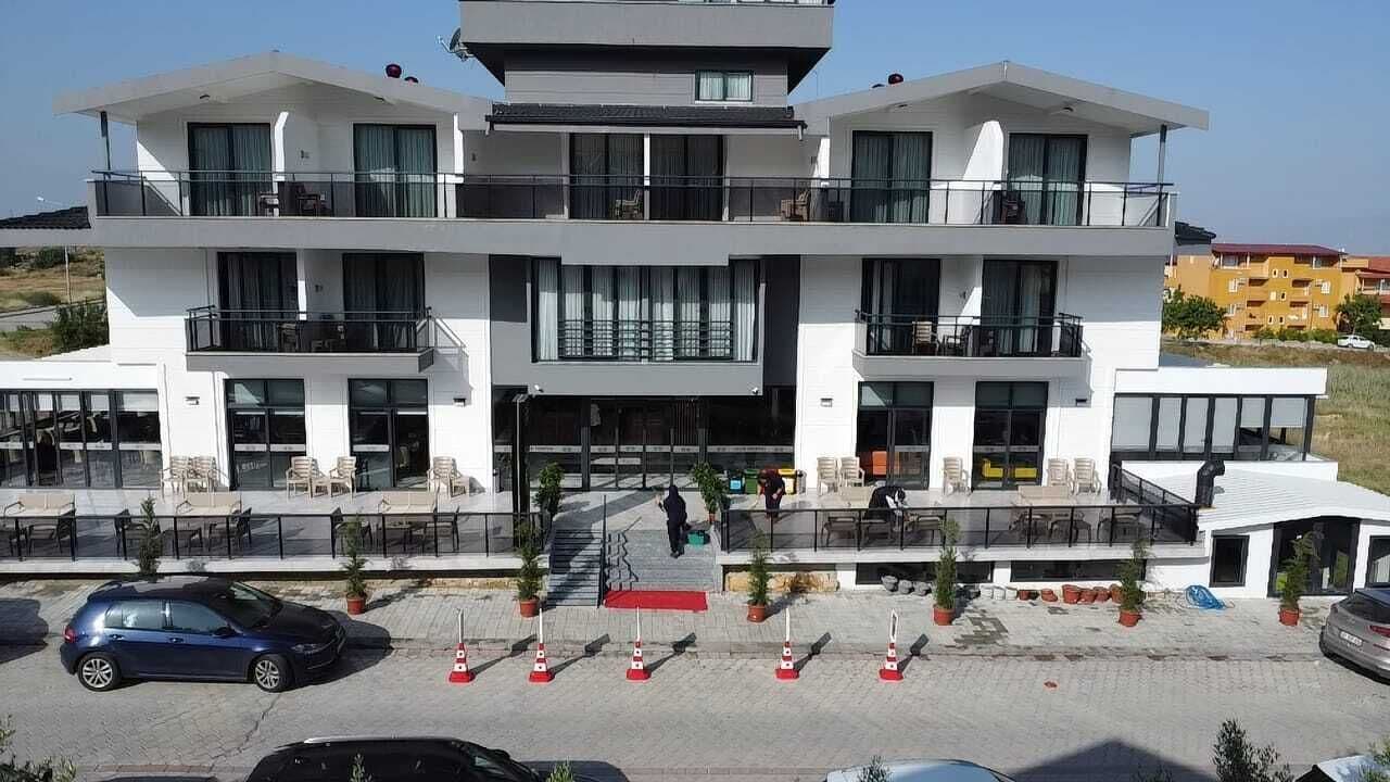 Un hotel moderno de varios pisos con balcones, mobiliario exterior y un estacionamiento.