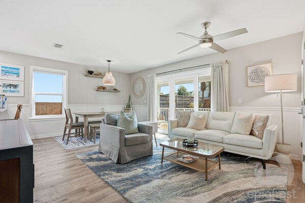 A spacious living room with a ceiling fan, a dining area with a table and chairs, a white sofa, and a coffee table.