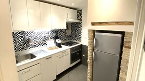 Una cocina moderna con armarios blancos, salpicadero a cuadros blanco y negro y una pared de acento de piedra.