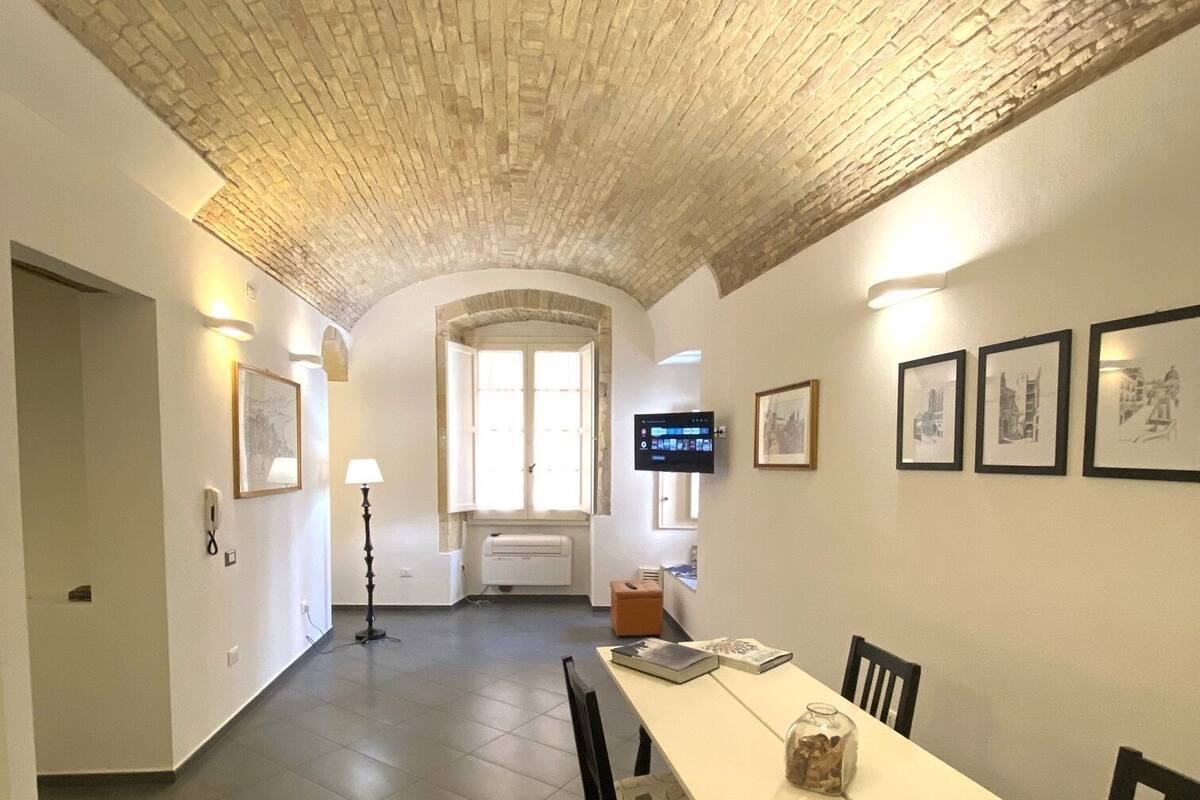 A dining area with a long table, chairs, and a TV screen.