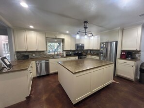 A modern kitchen with white cabinets, stainless steel appliances, and a large island. - Huge property with Lake Access! 8 separate sleeping spaces, 4 baths! (Kingsland)