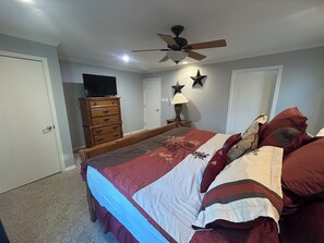 A bedroom with a bed, dresser, ceiling fan, star decorations, and a lamp. - Huge property with Lake Access! 8 separate sleeping spaces, 4 baths! (Kingsland)