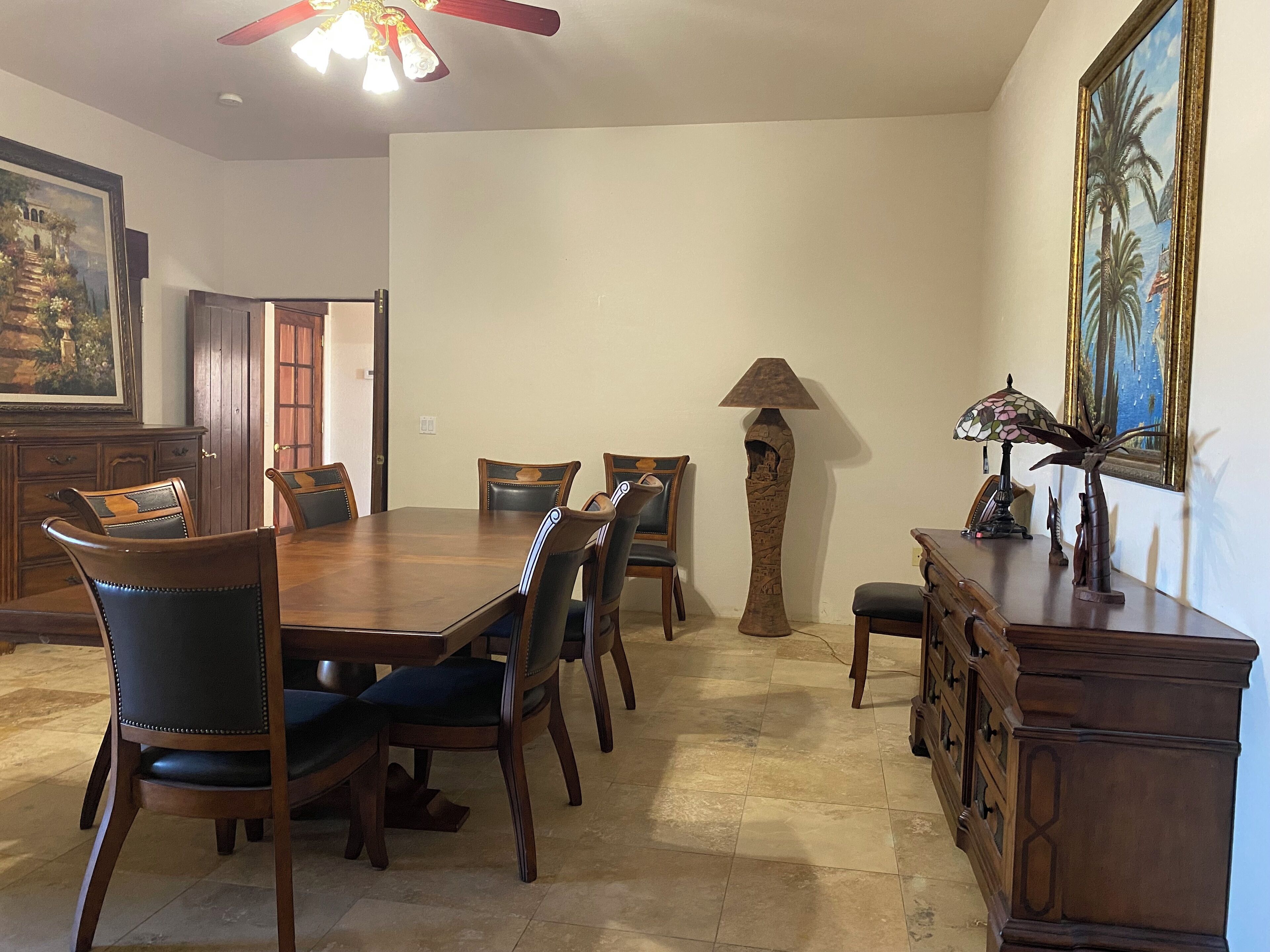 A dining area with a wooden table, chairs, a tall floor lamp, and a painting on the wall.