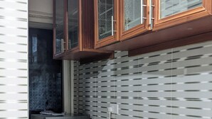 A compact kitchen with a refrigerator, wooden cabinets, and a patterned backsplash.