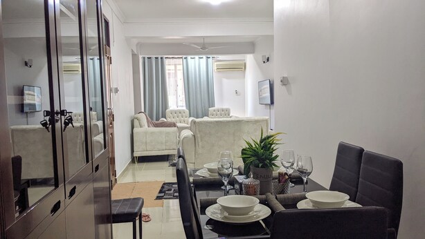 A dining area with a table set for four, a sofa, and a TV in the background.