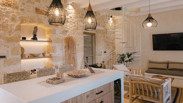 A modern kitchen with a white countertop, wooden cabinets, and hanging pendant lights. - Villa Aldea - Luxury Boho Style (Rethymno)