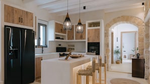 A modern kitchen with a central island, wooden cabinets, and pendant lighting. - Villa Aldea - Luxury Boho Style (Rethymno)