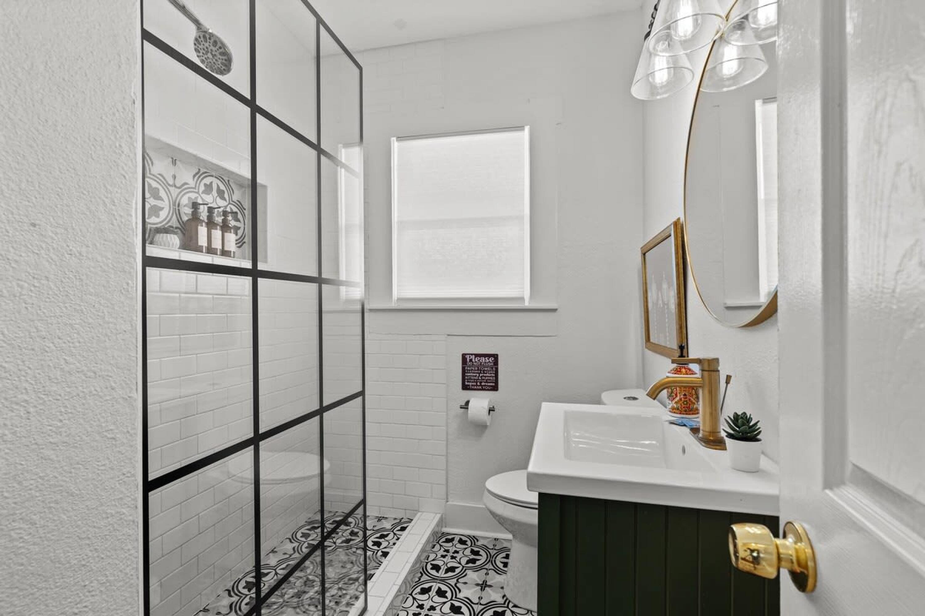 A bathroom with a white sink, a gold faucet, a mirror, and a toilet.