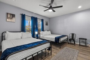 A room with two beds, a ceiling fan, a view of the city, and a chair. - Retreat to a Brand-new Downtown Home 4BR 3BA (San Antonio)