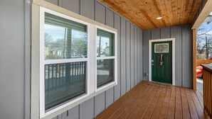 A covered porch with a wooden ceiling and grey siding walls. - Retreat to a Brand-new Downtown Home 4BR 3BA (San Antonio)