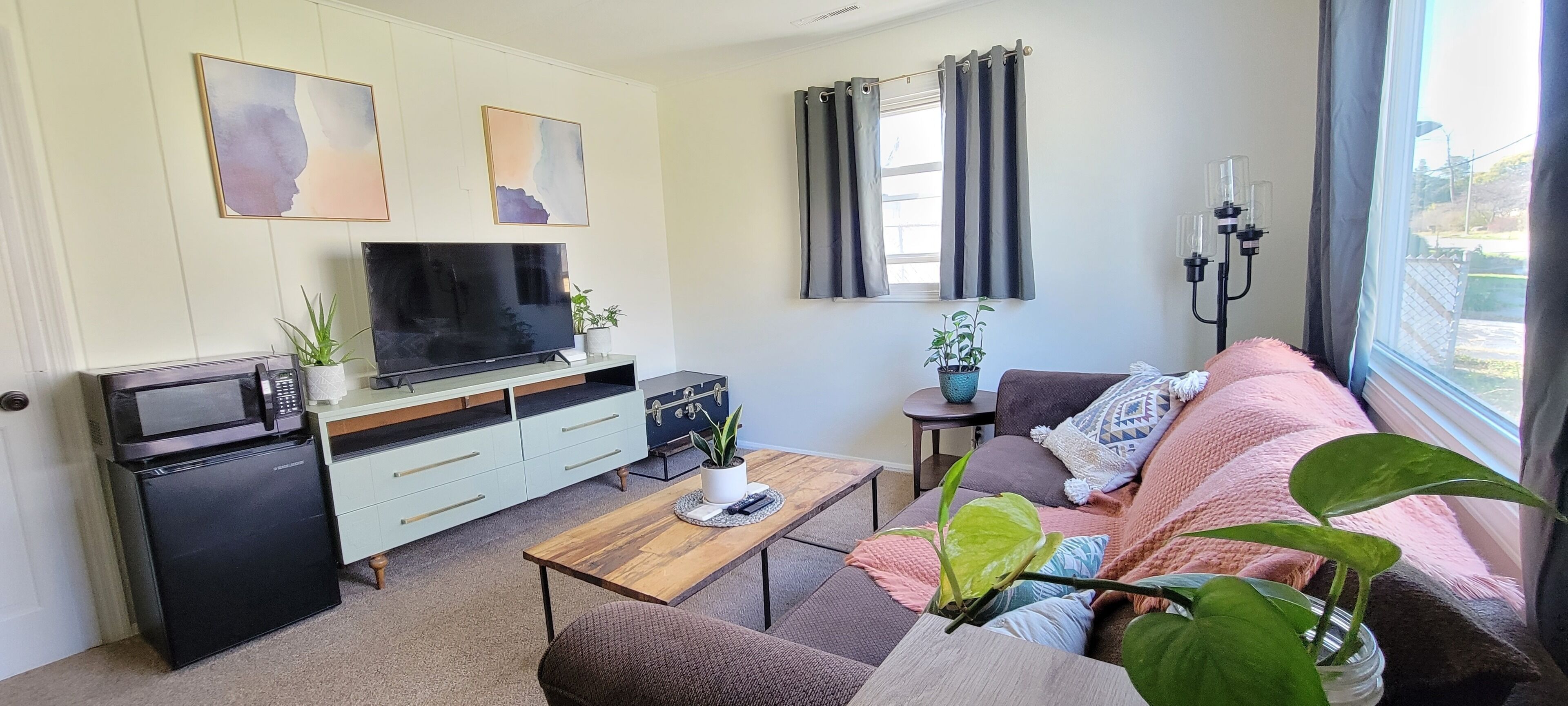 Un espacio habitable compacto con una televisión de pantalla plana, una kitchenette pequeña, un sofá y una mesita de centro.