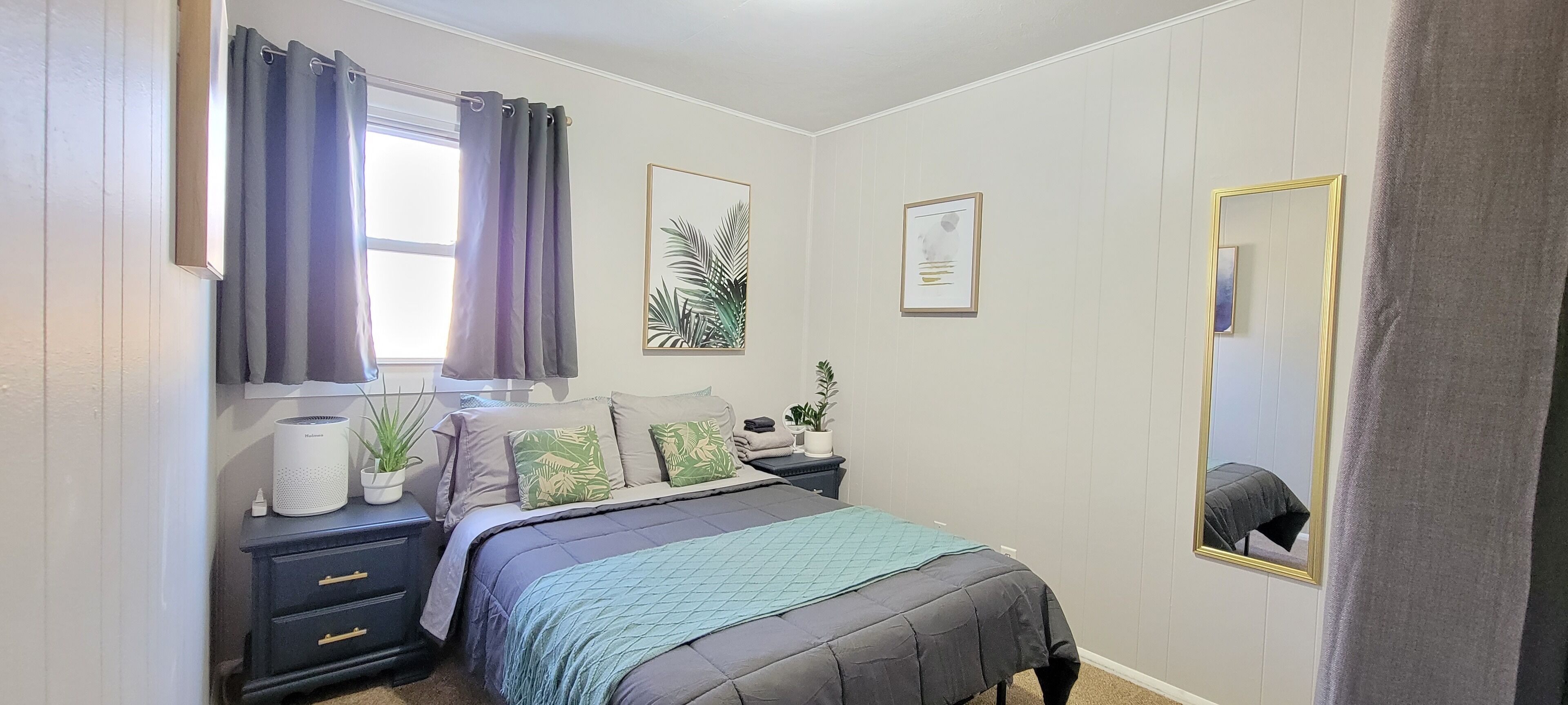 Una camera da letto con un letto, comodini, una finestra con tende, uno specchio e decorazioni alle pareti.
