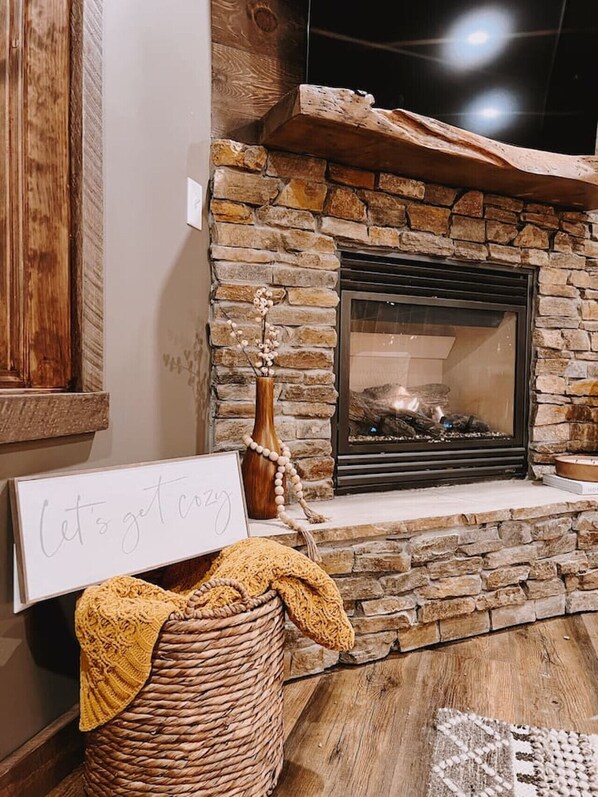 A stone fireplace with a sign reading "Let's get cozy" and a woven basket on the floor. - Cozy two bedroom cottage with indoor fireplace. (Crosslake)