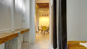 A narrow hallway with a wooden bench, a dining area with yellow chairs, and a kitchen with hanging pendant lights. - 377 Suite Stella - Superb apartment in Paris (Paris 03 Temple)