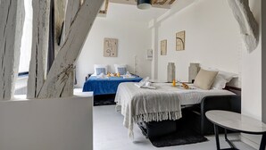 A modern bedroom with two beds, a dining table, and a small seating area. - 377 Suite Stella - Superb apartment in Paris (Paris 03 Temple)