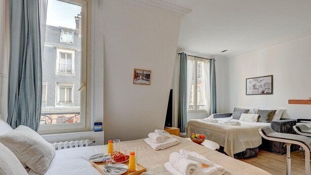 Ein Hotelzimmer mit zwei Betten, einem Essbereich mit Frühstück und Blick auf Gebäude.