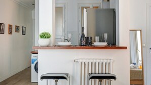 Eine moderne Küche mit Einbauofen, Spüle und Arbeitsplatte. Auf der Arbeitsplatte steht ein Topfpflanze und eine Champagnerflasche.