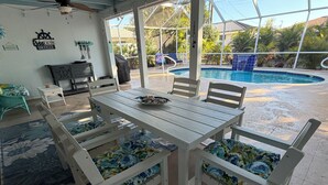 Ein überdachter Essbereich mit einem Pool im Hintergrund.
