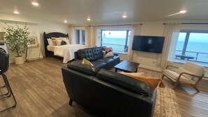 A modern hotel room with a large bed, a black leather sofa, a TV, and a view of the ocean. - Location and panoramic lake views will make for an unforgettable experience.  (Duluth)