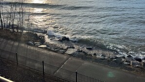 A coastal view with a clear sky, calm sea, and a paved walkway with a metal railing. - Location and panoramic lake views will make for an unforgettable experience.  (Duluth)