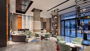 A modern interior with a seating area, a large bookshelf, and a view through a glass wall.