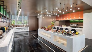 A modern kitchen with a buffet setup, marble flooring, and a view of greenery outside.