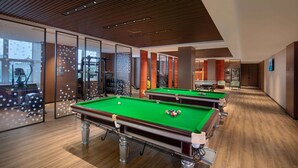 A pool table area with multiple tables, exercise equipment, and a view through a glass wall.