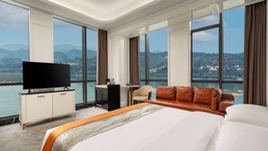 A hotel room with a large bed, a TV, a sofa, and a desk. - Ramada By Wyndham Yichang Riverside (Yichang)