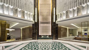 A spacious lobby with a geometric patterned floor, marble walls, and a central glass partition. - Ramada By Wyndham Yichang Riverside (Yichang)