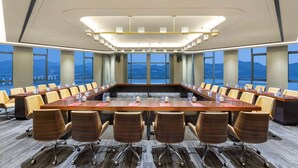 A conference room with a long table, multiple chairs, and large windows offering a city view. - Ramada By Wyndham Yichang Riverside (Yichang)