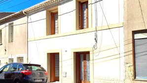 A two-story building with a tiled roof, a parked Citroen car, and visible electrical wiring. - L'ase et la Tuca (Bessan)