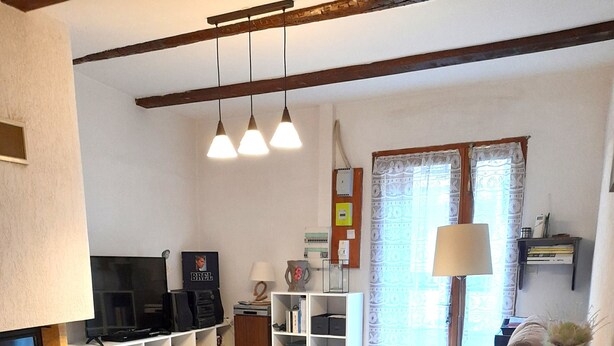 A living room with a sofa, a wooden dining table, a TV, and a bookshelf. - L'ase et la Tuca (Bessan)