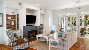 Una sala de estar con chimenea, televisor, sofá y sillón.
