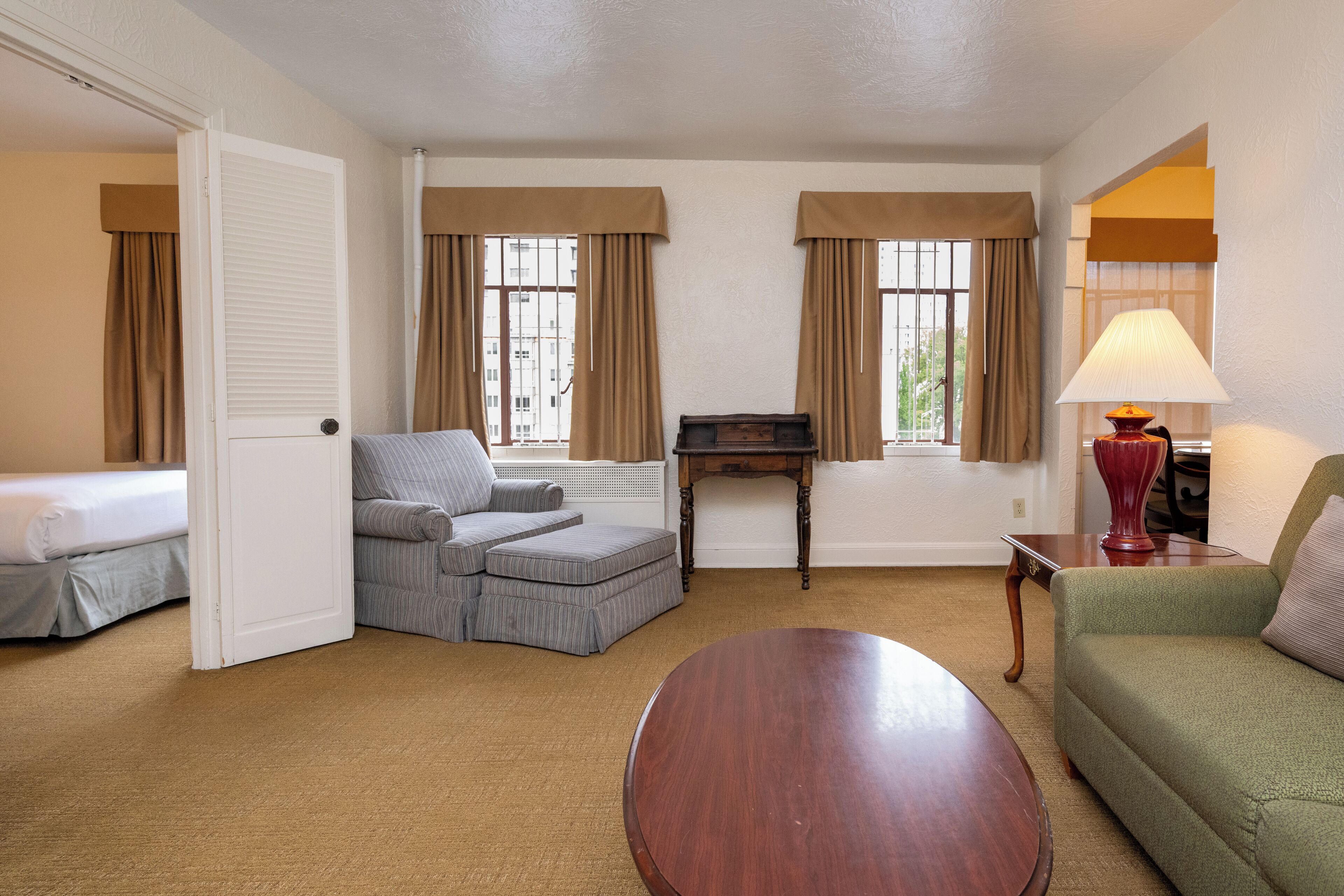 Une chambre d’hôtel avec un canapé, un fauteuil, une petite table, une lampe et un lit.