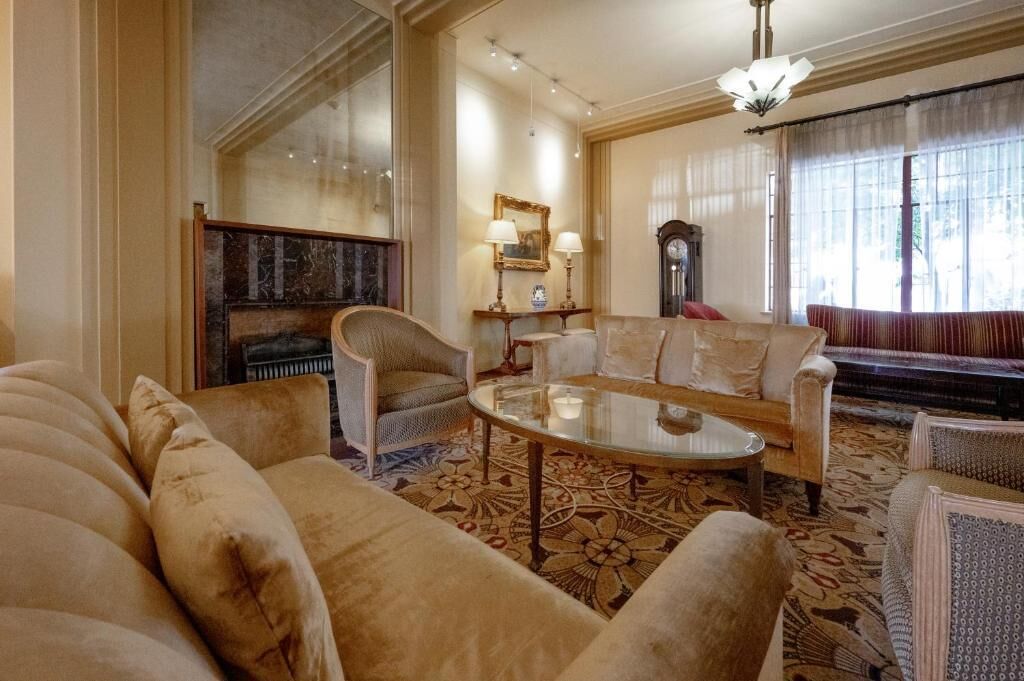 Een ruime woonkamer met een grote bank, een ronde salontafel en een piano op de achtergrond.