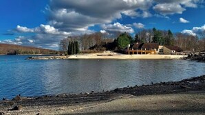 Une propriété située au bord d’un lac, avec un bâtiment doté d’une grande véranda et d’un mât pour drapeau.