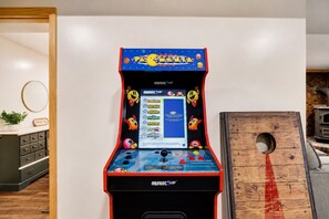 Una máquina arcade de Pac-Man en una habitación con un mueble de madera y un espejo circular en la pared.