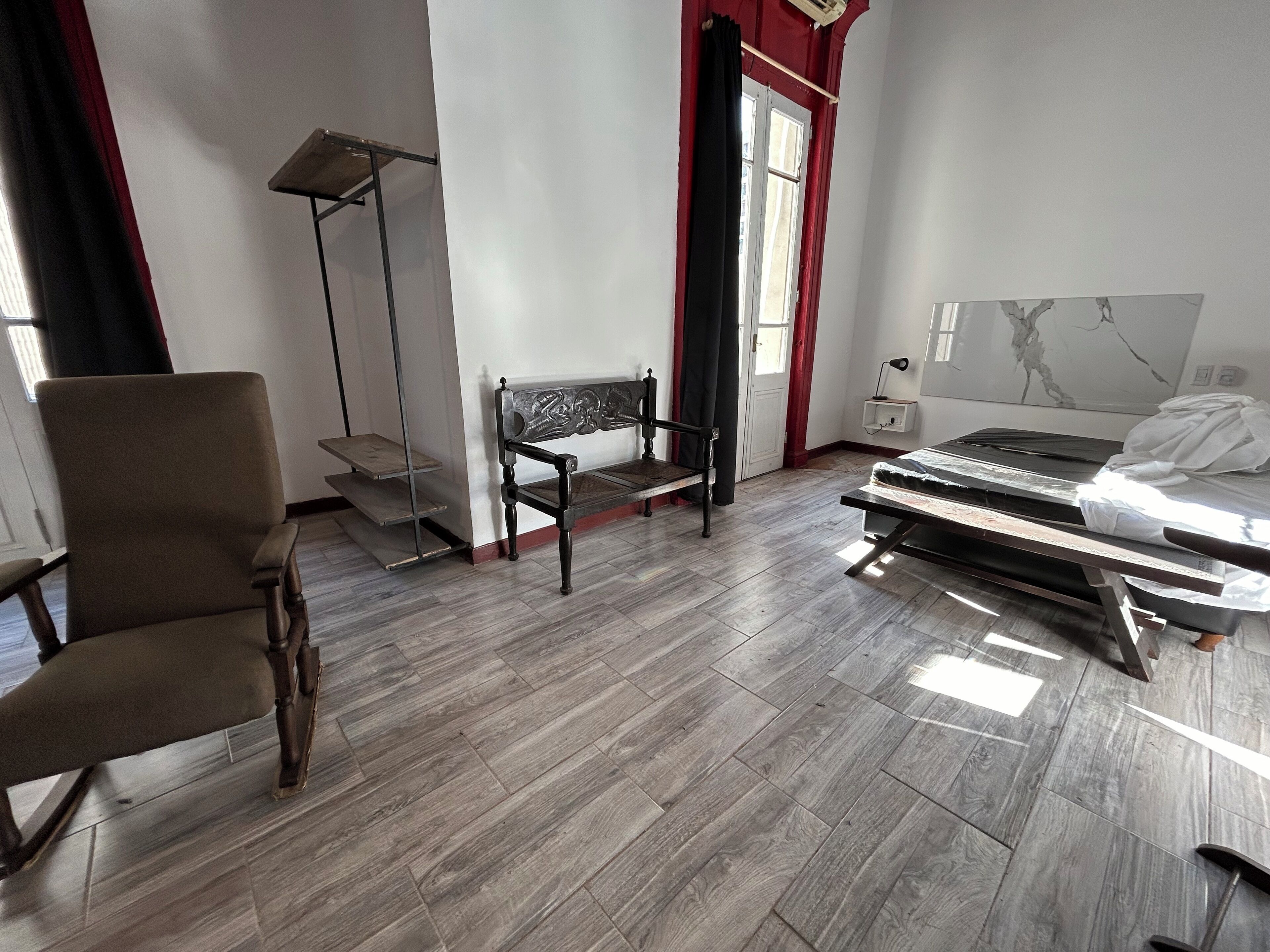A bedroom with a bed, a chair, a floor lamp, and a small table.