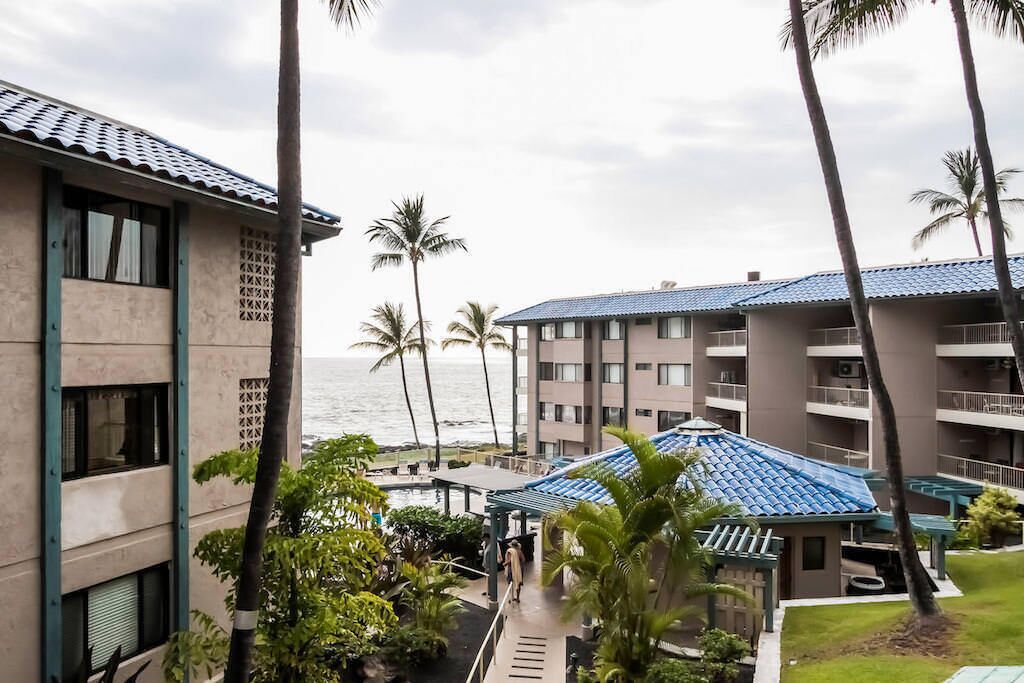 A hotel with multiple floors, a pool area, and a view of the ocean.