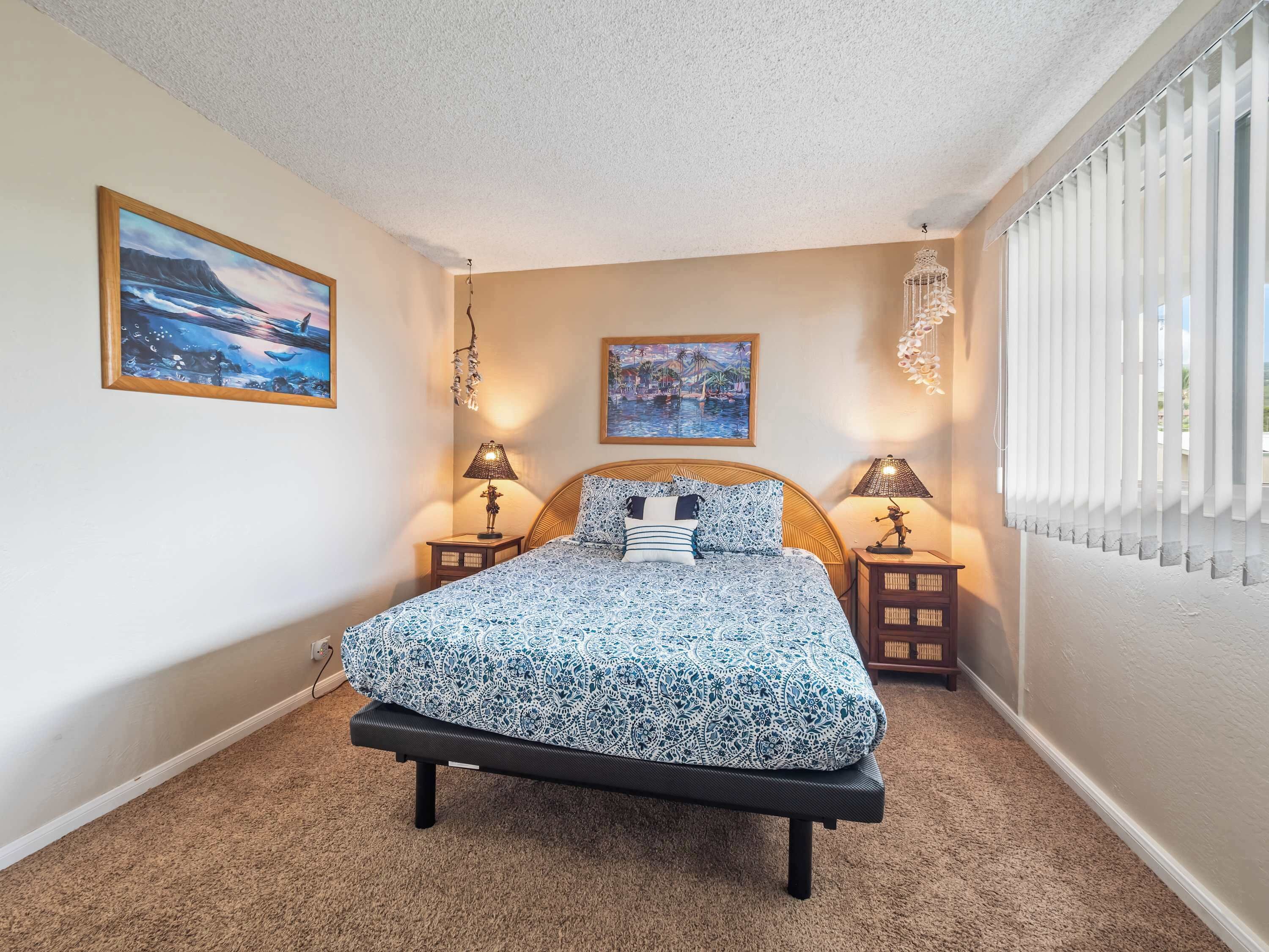 A bedroom with a bed, two bedside tables, two lamps, and two wall-mounted paintings.