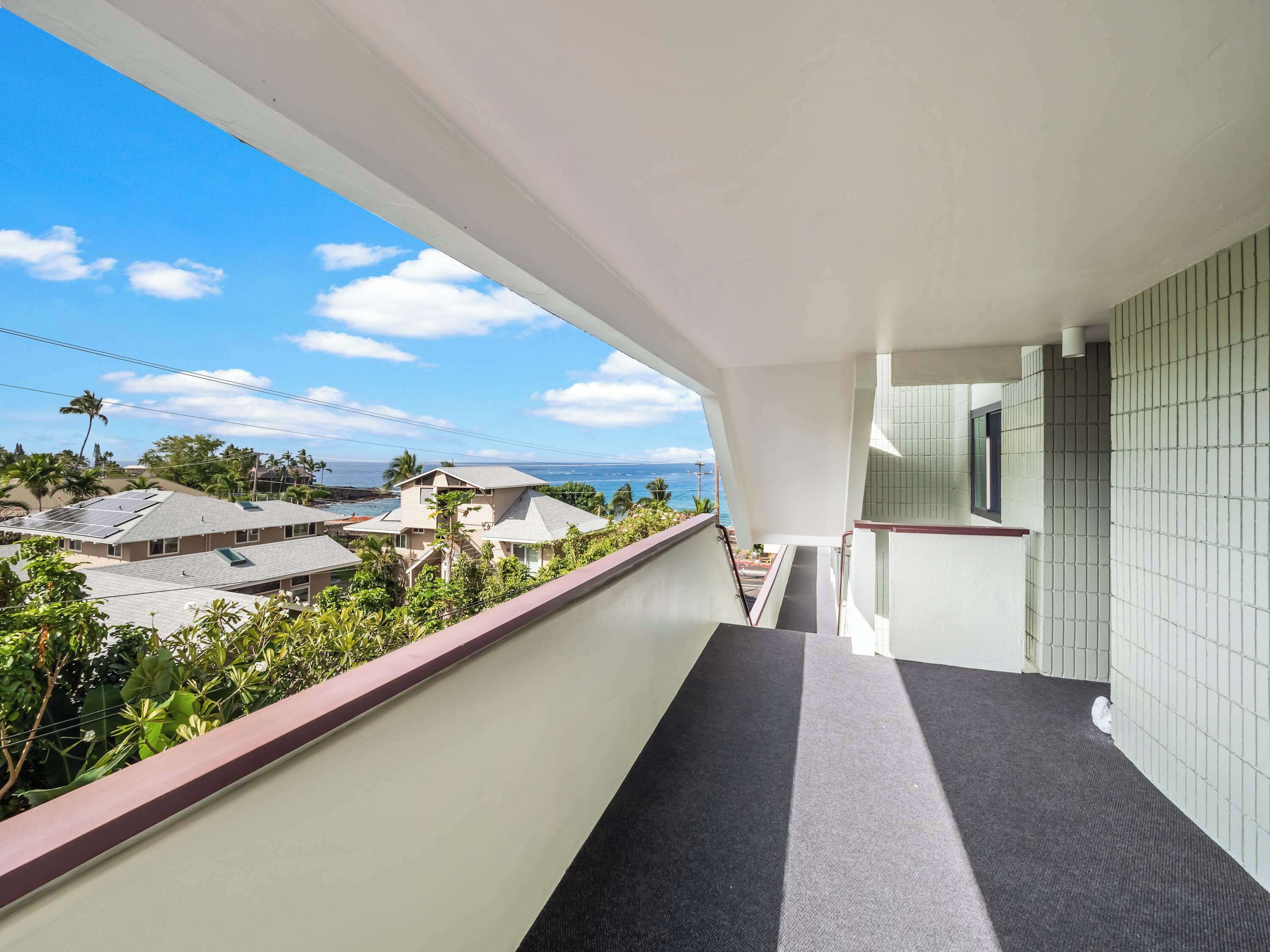 A balcony with a view of a residential area and the ocean.