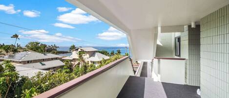A balcony with a view of a residential area and the ocean.
