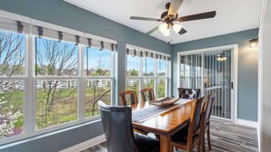 Un espace repas comprenant une grande table, des chaises et un ventilateur de plafond.